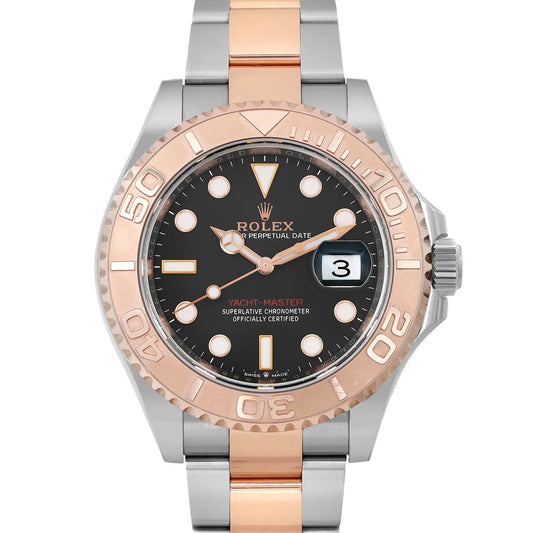 An image of a pre-owned Rolex Yacht-Master men's wristwatch, viewed from the front at a close-up angle that centers on the watch face. The watch features a black dial with a date indicator at the 3 o'clock position and luminous hands. It's encased in a rose gold bezel with a two-tone rose gold and steel bracelet. The watch displays good condition with light signs of wear such as minor scratches. Visible on the dial is the Rolex logo and the words "Perpetual Date" and "Yacht-Master."